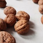 A detailed close-up of fresh whole walnuts scattered on a white background.