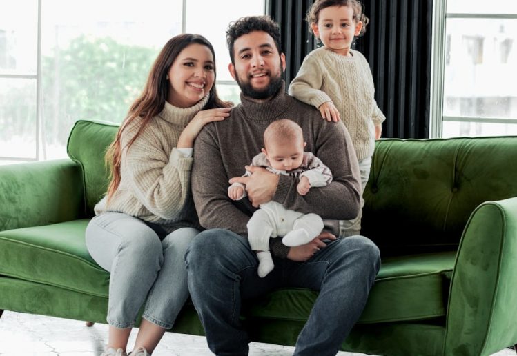 a family sitting on a green couch in a living room
