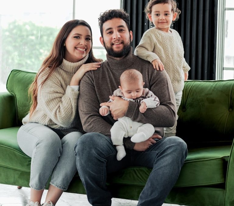 a family sitting on a green couch in a living room