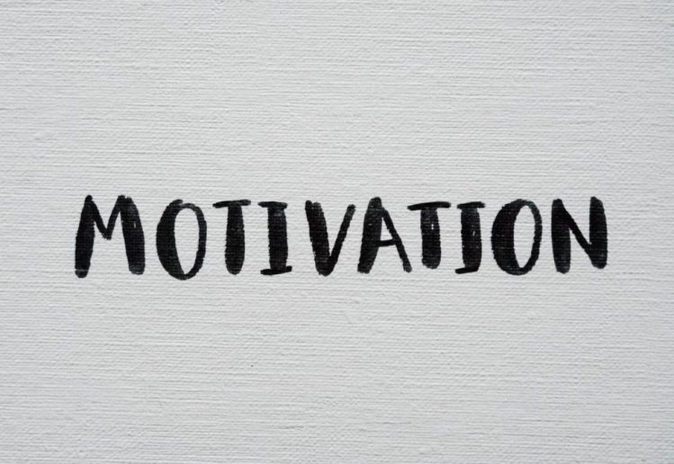 Inspirational word 'Motivation' in black on a white textured canvas background.